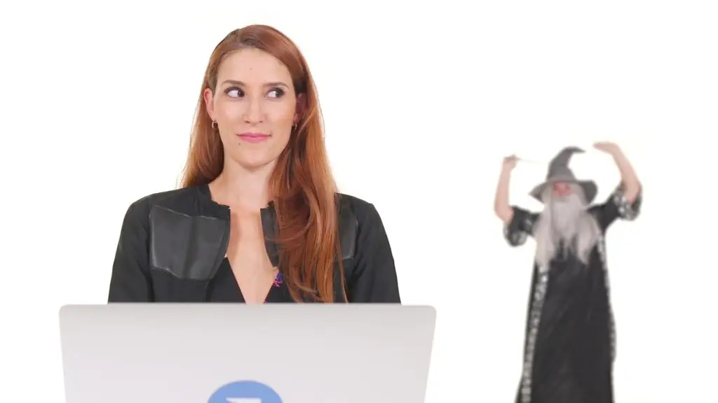 A wizard celebrates behind a woman at the computer