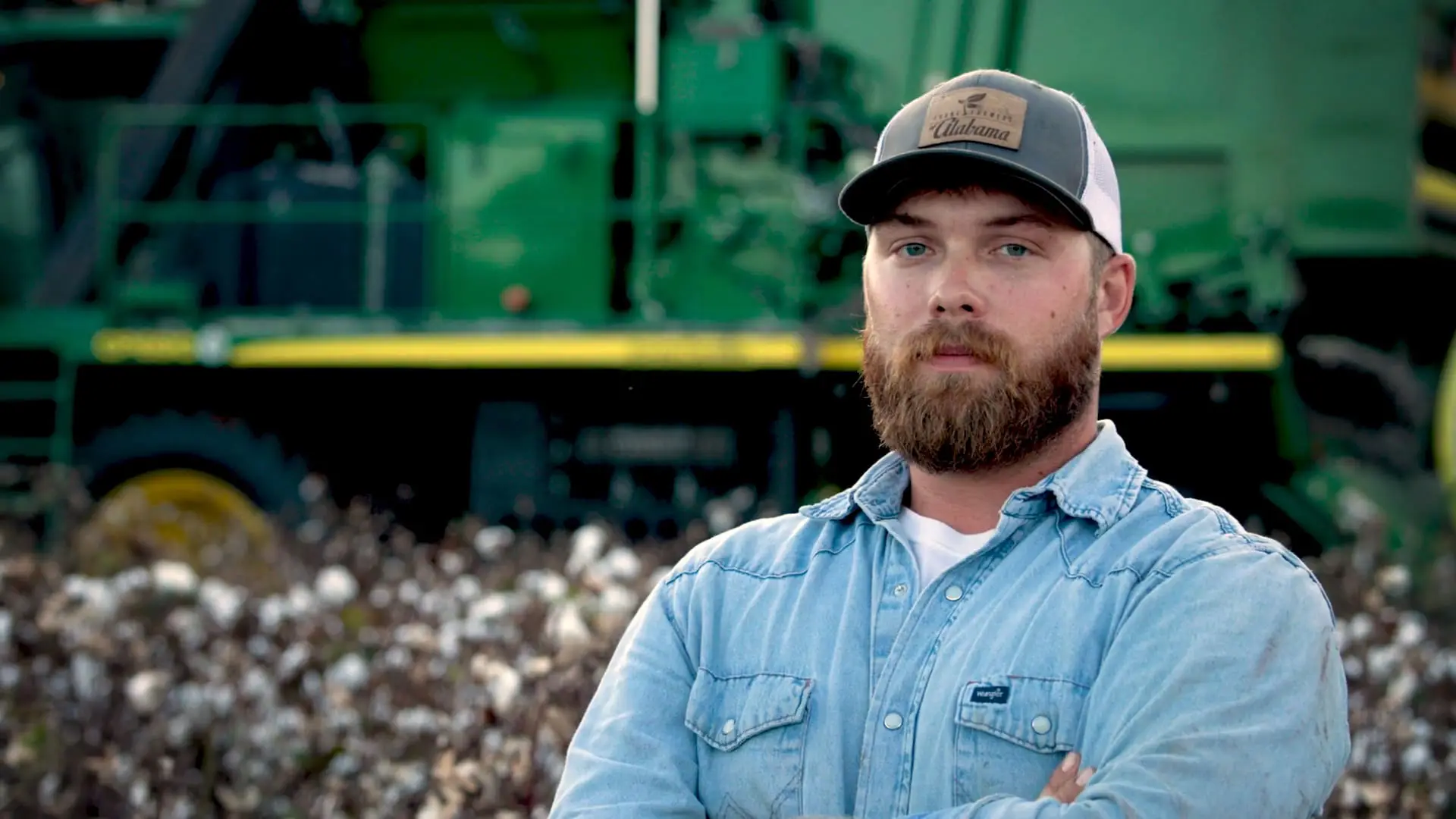 Portrait of a cotton farmer standing in front of his tractor with arms crossed